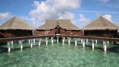 Su Villaları (Bungalovlar) ve yaz günü Maldivler 'deki tropik sahildeki ahşap köprü 
