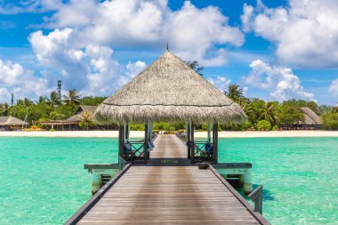 MALDIVES - JUNE 24, 2018: Water Villas (Bungalows) and wooden bridge at Tropical beach in the Maldives at summer day clipart