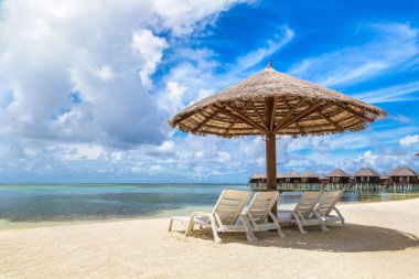 MALDIVES - JUNE 24, 2018: Wooden sunbed and umbrella on tropical beach in the Maldives at summer day clipart