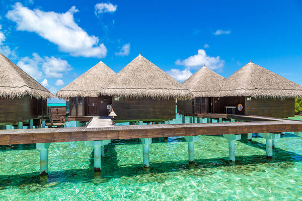 MALDIVES - JUNE 24, 2018: Water Villas (Bungalows) and wooden bridge at Tropical beach in the Maldives at summer day