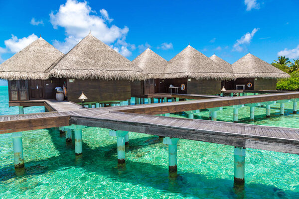 MALDIVES - JUNE 24, 2018: Water Villas (Bungalows) and wooden bridge at Tropical beach in the Maldives at summer day