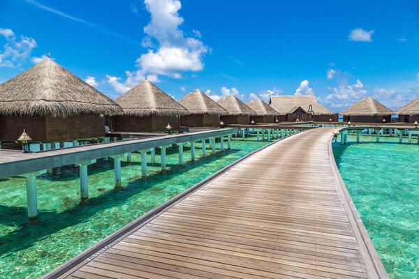 MALDIVES - JUNE 24, 2018: Water Villas (Bungalows) and wooden bridge at Tropical beach in the Maldives at summer day