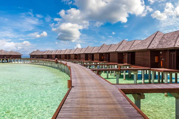 stock image MALDIVES - JUNE 24, 2018: Water Villas (Bungalows) and wooden bridge at Tropical beach in the Maldives at summer day
