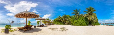 Panorama of Wooden sunbed and umbrella on tropical beach in the Maldives at summer day clipart