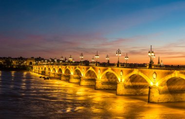 Panorama of Pont de pierre, old stony bridge in Bordeaux in a beautiful summer night, France clipart