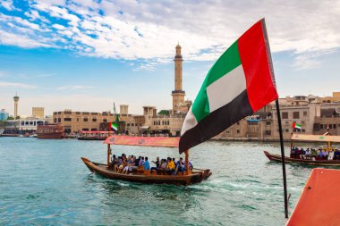 DUBAI, BAE - 5 Nisan 2020: Birleşik Arap Emirlikleri bayrağı Abra 'ya karşı - Birleşik Arap Emirlikleri' nin Dubai Körfezi 'ndeki eski geleneksel ahşap tekne