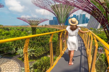 SINGAPORE - 23 Haziran 2019 Singapur Körfezi yakınlarındaki Gardens 'taki Skyway Köprüsü' nde beyaz elbise ve hasır şapka giyen kadın gezgin