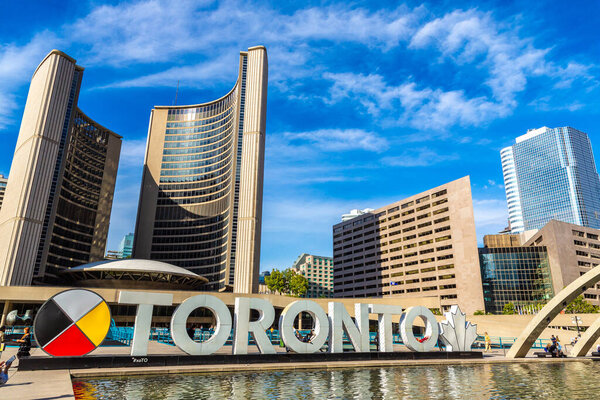 ТОРОНТО, КАНАДА - 2 апреля 2020 года: знак Торонто и ратуша на площади Натана Филлипса в Торонто в солнечный день, Онтарио, Канада