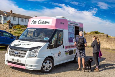 NORTHUMBERLAND, İngiltere - 15 Ağustos 2025: Güneşli bir günde Craster Village, Northumberland, İngiltere 'de bir köpeğe dondurma servisi yapan geleneksel dondurma kamyonu