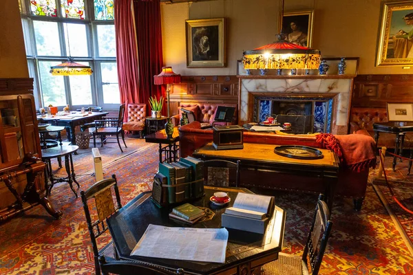 NORTHUMBERLAND, İngiltere - 13 Ağustos 2025: Vitray pencereli tarihi Viktorya kütüphanesi, antika mobilyalar ve Northumberland, İngiltere 'deki Cragside House içinde klasik dekorasyon