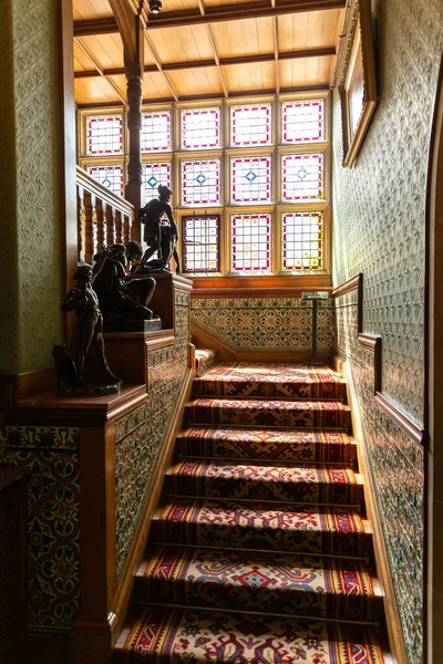 NORTHUMBERLAND, İngiltere - 13 Ağustos 2025: Northumberland, İngiltere 'deki tarihi Cragside House' da vitray ve desenli halı ile dekore edilmiş Viktorya dönemi merdivenleri