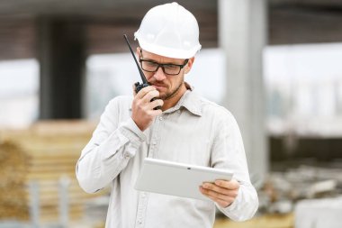 Erkek baş giyen beyaz Emanet hardhat volki tolki ve şantiye teftiş tablet ile mühendislik. Teknoloji, geliştirme ve İnşaat Sanayi kavramı
