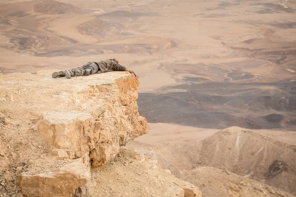 Man is lying on the edge of Ramon crater cliff at  Negev desert, — 图库照片