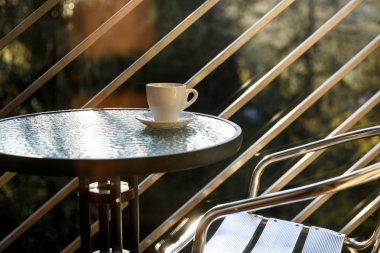 Beyaz seramik kahve fincanı balkon kahve masasında duruyor.