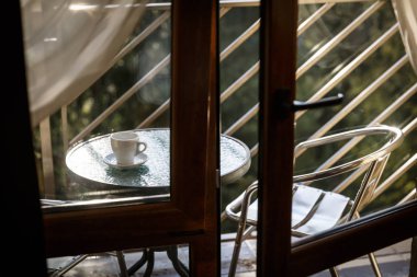 Beyaz seramik kahve fincanı balkon kahve masasında duruyor.