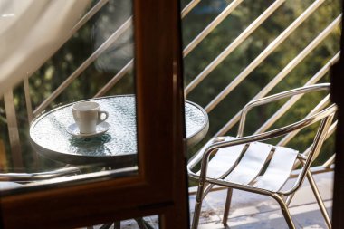 Beyaz seramik kahve fincanı balkon kahve masasında duruyor.