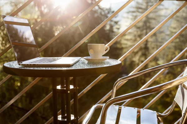 Taza de té o café blanco y un ordenador portátil en una mesa de café balcón —  Fotos de Stock