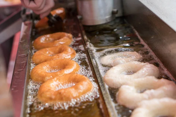 Preparação de rosquinhas fritas em um óleo quente . — Fotografia de Stock