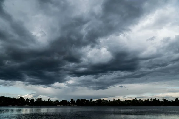 Donkere stormachtige wolken voor de onweer over de rivier — Stockfoto