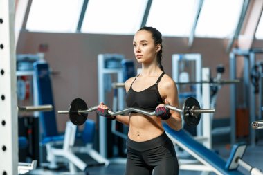 Bir spor salonunda Kadın bir halter ile perfoms egzersizleri 