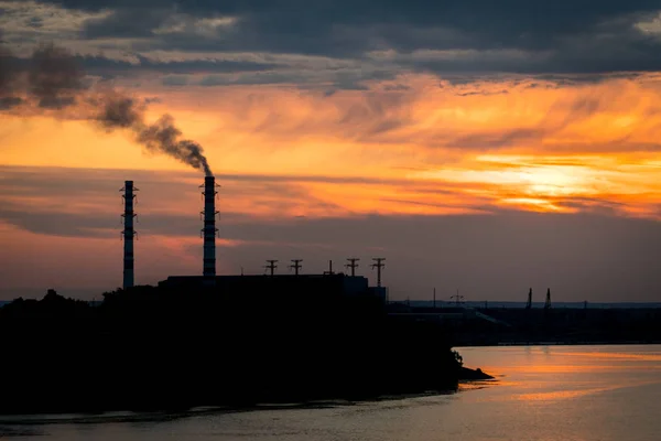 Закат силуэт промышленного завода с дымящейся трубой — стоковое фото