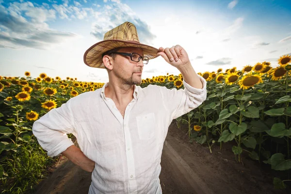 Portrait d'un agriculteur dans un chapeau de paille dans un champ de tournesol . — Photo
