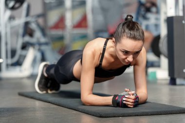 Genç sportif kadın bir spor salonunda tahta egzersiz yapıyor