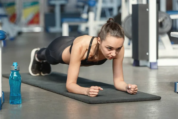 Joven mujer deportiva haciendo ejercicio de tablón en un gimnasio —  Fotos de Stock