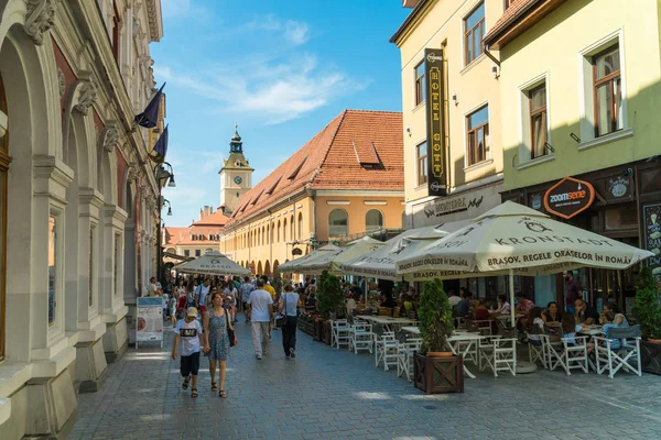 Persone a piedi nel centro della città vecchia di Brasov con negozi e — Foto Stock