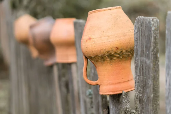 Brocche di argilla marrone appese in una recinzione di legno in Ucraina . — Foto Stock