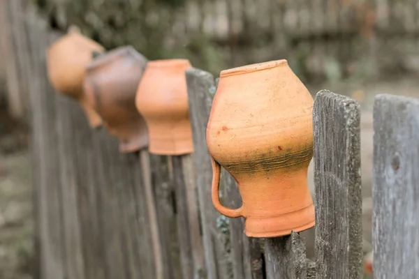 Καφέ πηλό κανάτες κρέμονται σε ένα ξύλινο φράχτη στην Ουκρανία. — Φωτογραφία Αρχείου