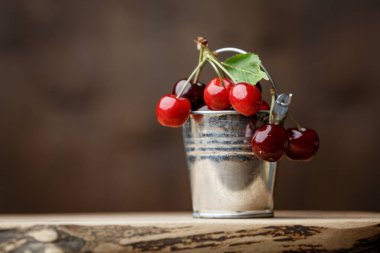 Küçük dekoratif metal kovada kiraz kahverengi ahşap arka planda ahşap bir tahtanın üzerinde