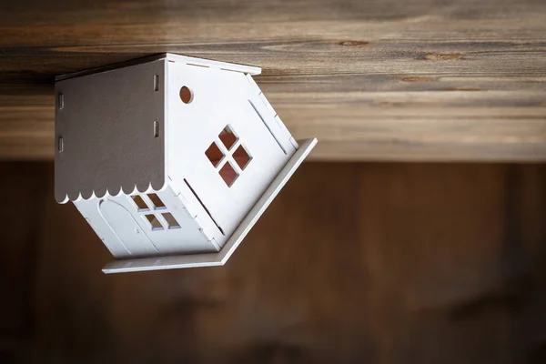 茶色の木製の背景に上下に三角形の屋根の上に家のステンドグラスの白いモデル 不動産のコンセプト — ストック写真