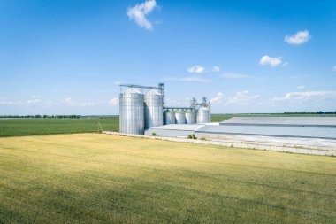 Yeşil buğday tarlasında modern bir tahıl asansörünün havadan görünüşü. Tarım ürünleri depolama kavramı