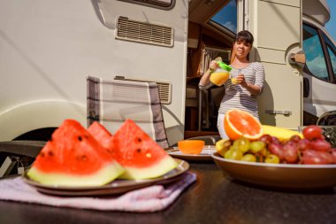 Aile tatil seyahat Rv, kamyonet ve karavan, karavan araba tatil tatil gezisi. Kadın portakal suyu bir bardak içki alıyor.