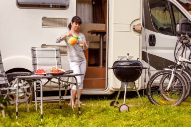 Aile tatil seyahat Rv, kamyonet ve karavan, karavan araba tatil tatil gezisi. Piknik açık barbekü ile. Kadın portakal suyu bir bardak içki alıyor.