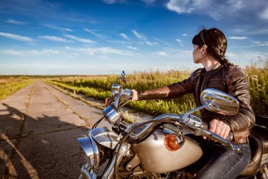 Motorcu kız bir deri ceket ve motosiklet üzerinde oturan güneş gözlüğü
