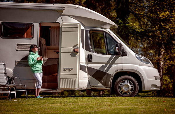 Woman is standing with a mug of coffee near the camper RV.