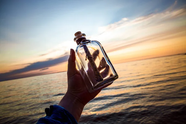 Mensagem na garrafa contra o pôr do sol — Fotografia de Stock