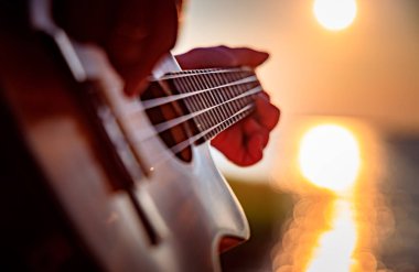 Gün batımında ukulele çalan kadın.