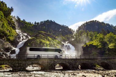 Tourist bus traveling on the road Latefossen Waterfall Odda Norw clipart
