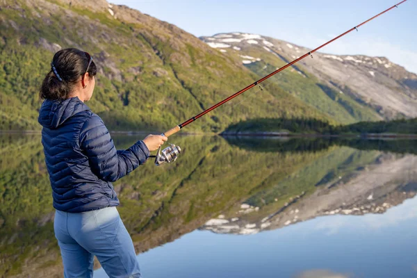 Femme pêche sur la canne à pêche filature en Norvège . — Photo