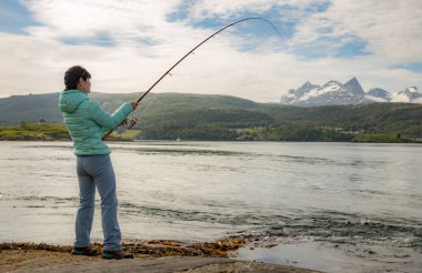 Woman fishing on Fishing rod spinning in Norway. clipart