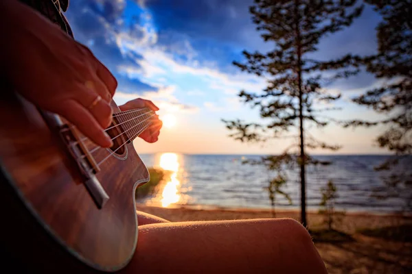 Kvinna vid solnedgången håller en ukulele — Stockfoto