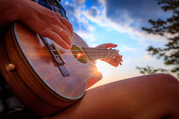 Kobieta o zachodzie słońca trzyma ukulele — Zdjęcie stockowe