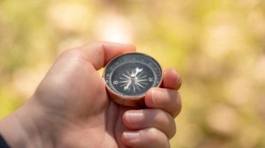 Gezgin el ormanda bir pusula tutuyor.