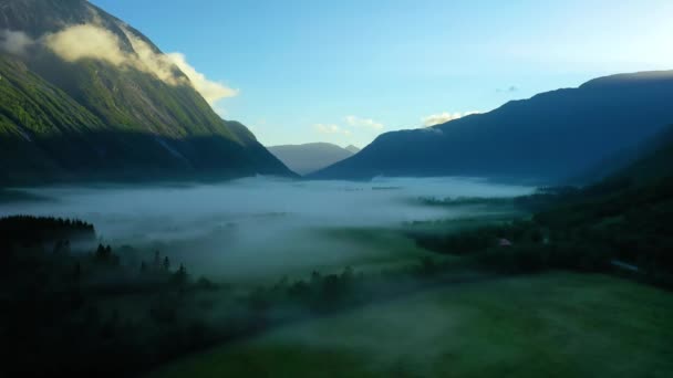 Névoa da manhã sobre o vale entre as montanhas à luz do sol. Nevoeiro e bela natureza das filmagens aéreas da Noruega. — Vídeo de Stock