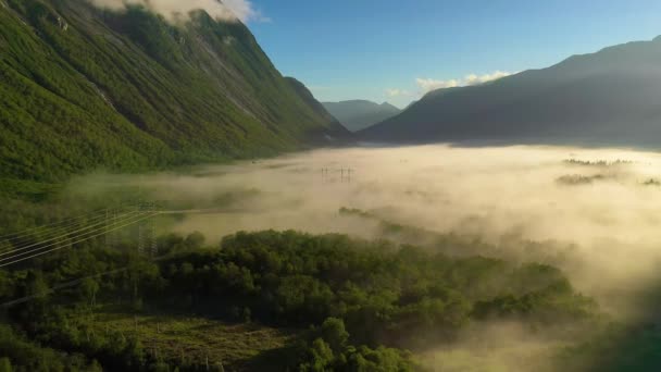 Névoa da manhã sobre o vale entre as montanhas à luz do sol. Nevoeiro e bela natureza das filmagens aéreas da Noruega. — Vídeo de Stock