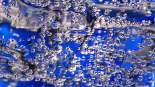 Glas vatten med is på en mörkblå bakgrund — Stockvideo
