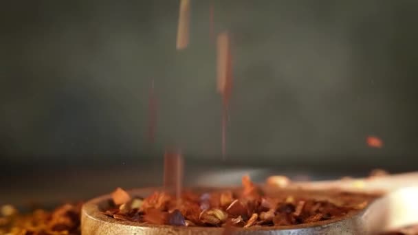 キッチンテーブルの上に木製のスプーンクローズアップで赤唐辛子のフレーク — ストック動画
